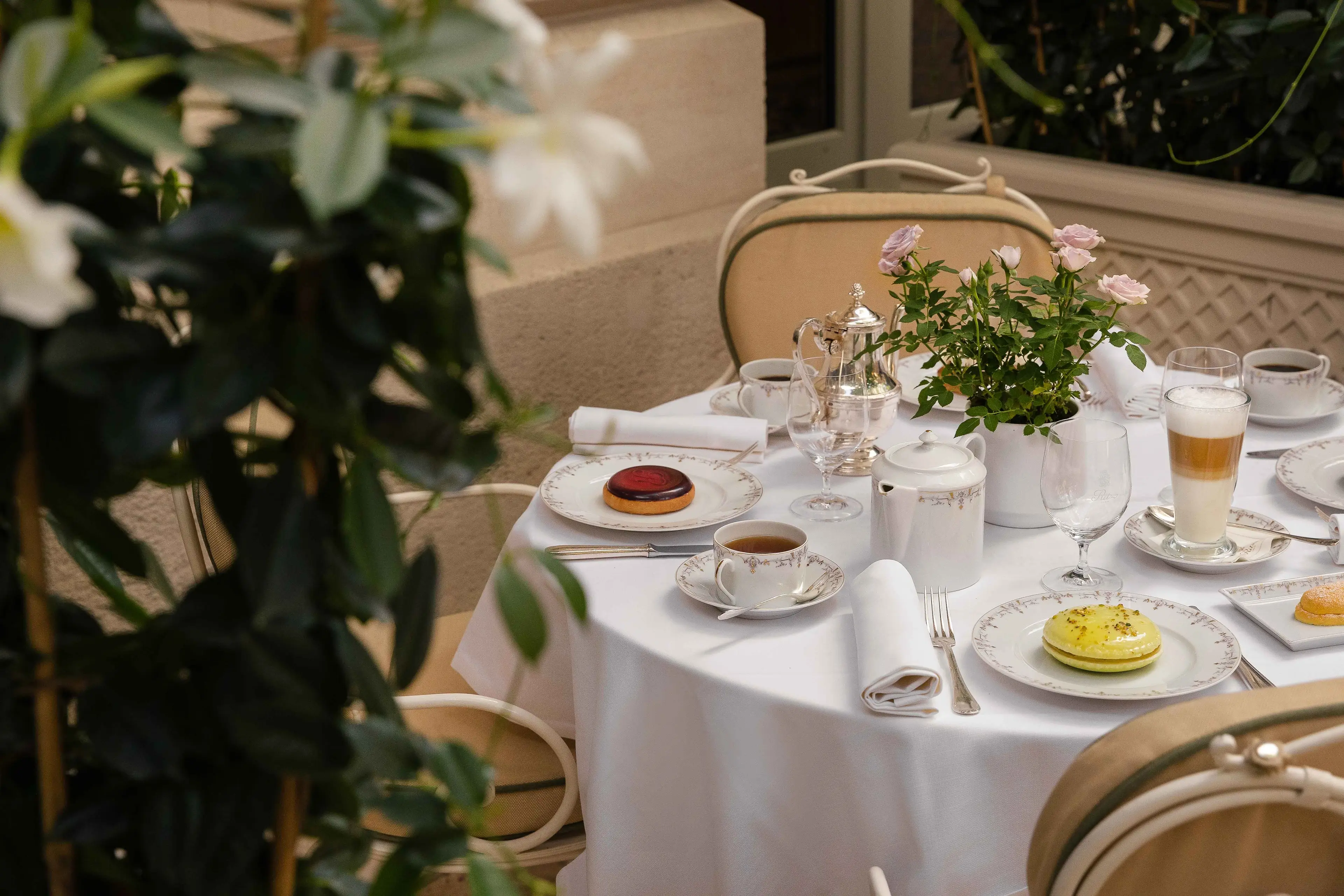 Table de tea time dressée dans le jardin du Ritz Paris, tasses à thé et pâtisseries